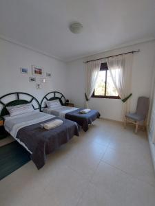 1 dormitorio con 2 camas, silla y ventana en L.A. Apartment, en Los Alcázares