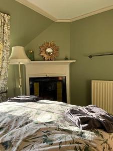 a bedroom with a bed and a clock on a fireplace at A charming, well appointed Edwardian Gate Lodge in Alyth