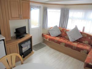 a living room with a couch and a tv at 6 Berth on Golden Sands (Westbrook Tahiti) in Ingoldmells