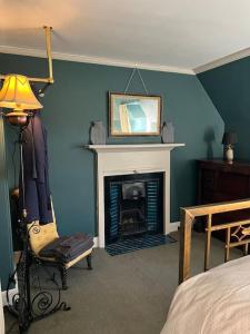 um quarto azul com uma lareira e uma cama em A charming, well appointed Edwardian Gate Lodge em Alyth