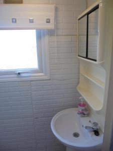 a white bathroom with a sink and a window at 6 Berth on Golden Sands (Westbrook Tahiti) in Ingoldmells