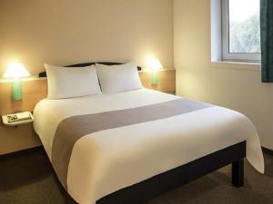 a large bed in a hotel room with two lamps at ibis Toulouse Pont Jumeaux in Toulouse