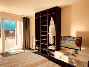 a bedroom with a bed and a tv in a room at Seehotel Riviera at Lake Lucerne in Gersau