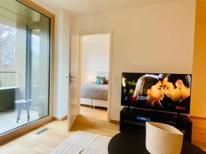 a living room with a flat screen tv and a bedroom at Luxury Brand New Flat with Terrace & Parking - RTL1 in Luxembourg