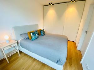 a small bedroom with a blue bed and a side table at Luxury Brand New Flat with Terrace & Parking - RTL1 in Luxembourg