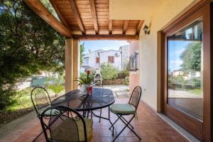 a patio with a glass table and chairs on a patio at Villetta Erica in Tanaunella