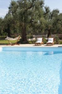 a swimming pool with two chairs and a hammock at Donna Lucrezia in Pezze di Greco