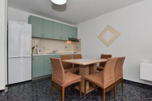 a kitchen with a table and chairs and a refrigerator at Apartment Ivo Kaurinovic in Zaton