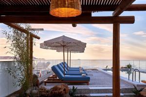 a group of blue lounge chairs and an umbrella at Rodo Seafront Villa with Heated private pool and jacuzzis by Volta Suites and Villas in Kokkíni Khánion