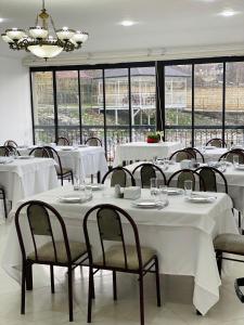 un comedor con mesas y sillas blancas y ventanas en Sultan Makan, en Çuxuryurd