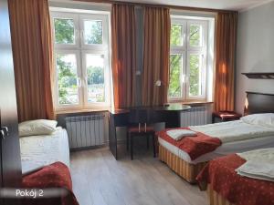 um quarto de hotel com duas camas, uma secretária e janelas em GLIWICKA 16 em Katowice