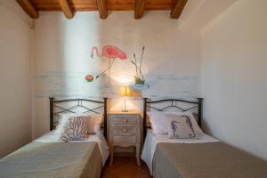 1 dormitorio con 2 camas y una pintura de un flamenco en Villetta Erica en Tanaunella