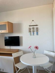 a kitchen with a white table and chairs and a table with flowers at Estudio apartamento LaLola in Matalascañas