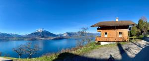 ジーグリスヴィルにあるCHALET EGGLEN "Typical Swiss House, Best Views, Private Jacuzzi"の水の横の丘の上の建物