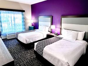 2 camas en una habitación de hotel con paredes púrpuras en La Quinta by Wyndham Pharr North McAllen, en Pharr