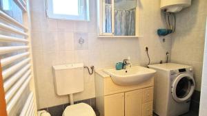 mała łazienka z umywalką i pralką w obiekcie Apartments Ana & Ivan w Krku