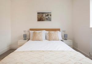 a white bedroom with a large bed with two night stands at Spacious En-suite Private Double Bedroom in Oxford