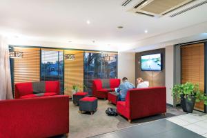 a lobby with two people sitting in red chairs at Rydges Kalgoorlie in Kalgoorlie