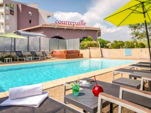 a swimming pool with chairs and an umbrella at ibis Styles Fréjus St Raphael in Fréjus