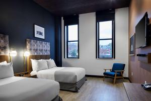 a hotel room with two beds and a chair at TRYP by Wyndham Pittsburgh/Lawrenceville in Pittsburgh