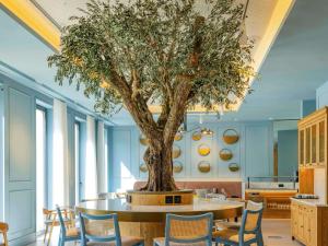 a table with a tree in the middle of a room at Mercure Porto Centro Aliados in Porto