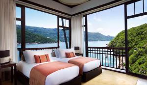 two beds in a room with large windows at Banyan Tree Cabo Marques in Acapulco