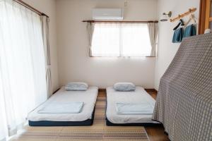 two beds in a room with a window at MaruHouse in Nachikatsuura