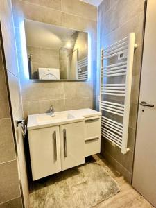 La salle de bains est pourvue d'un lavabo blanc et d'un miroir. dans l'établissement Beautiful apartment - Air Conditionning -Pool -10min Beach -Parking near, à Antibes