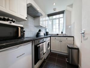 een keuken met een magnetron en een vaatwasser bij Wonderful Pavilion View 1BR by Sullivan Stays in Brighton & Hove