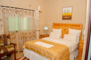 a bedroom with a bed and a chair and a window at ROYAL SHALOM HOTEL in Lusaka