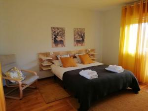 a bedroom with a large bed and a chair at Lar de Yago - Casa in Barreiros