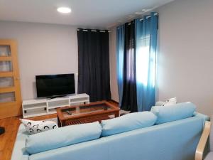 a living room with a blue couch and a television at Lar de Yago - Casa in Barreiros