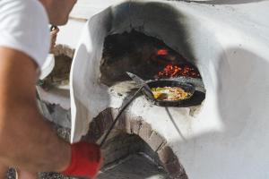 a man is cooking food in a stone oven at Nisi Glamping in Paralia Rachon