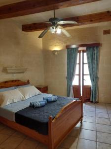 a bedroom with a bed with a ceiling fan at MJ Farmhouse B&B in Xagħra