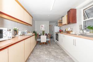 a kitchen with white cabinets and a table in it at Xtra Large 4 Bedroom House, near Excel, London City and 5 walk to Train Station in London