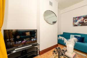 a living room with a blue couch and a mirror at Xtra Large 4 Bedroom House, near Excel, London City and 5 walk to Train Station in London