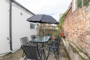 a table and chairs with an umbrella on a patio at Xtra Large 4 Bedroom House, near Excel, London City and 5 walk to Train Station in London