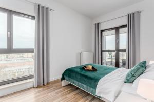 City View Apartments في وارسو: غرفة نوم بيضاء بها سرير ونوافذ كبيرة