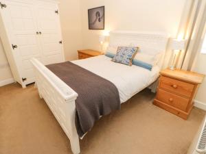 1 dormitorio con 1 cama blanca grande y mesita de noche en Lower Driftwood, en Amble