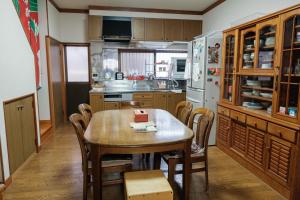 eine Küche mit einem Tisch und Stühlen sowie einem Kühlschrank in der Unterkunft MaruHouse in Nachikatsuura