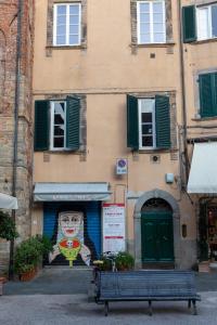 ein Gebäude mit einem Wandbild auf der Seite mit einer Bank in der Unterkunft a casa di Ale in Lucca
