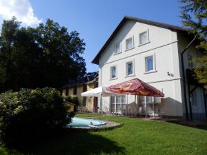 a house with an umbrella and a swimming pool at Penzion Ráj in Blíževedly