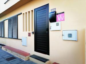 eine schwarze Tür mit einem TV auf der Seite eines Gebäudes in der Unterkunft Casa Amaia in Arrecife
