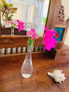a glass vase with pink flowers sitting on a table at Ltorec in Nyali