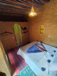 - une chambre avec un lit et un lustre dans l'établissement Dar Yaya, à M'Hamid El Ghizlane