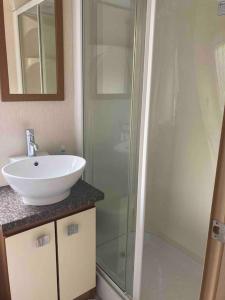 a bathroom with a sink and a glass shower at 2 bedroom chalet in Chwilog on the Llyn Peninsula in Pwllheli