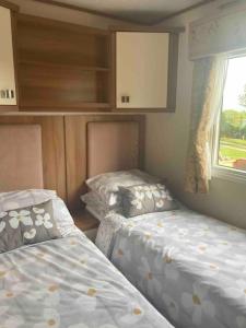 two beds in a small room with a window at 2 bedroom chalet in Chwilog on the Llyn Peninsula in Pwllheli