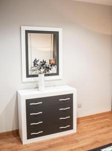 a dresser with a mirror and a vase on it at Apartamento Cuatro Caminos in Chantada