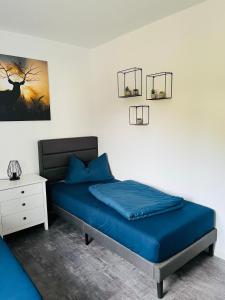 - une chambre avec un lit bleu et une table de nuit dans l'établissement Ferienwohnung am Tor zum Thüringer Wald 2, à Plaue