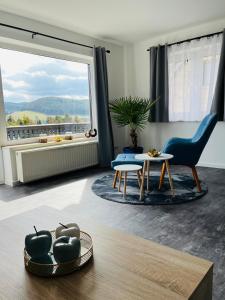 een woonkamer met een groot raam en een blauwe stoel bij Ferienwohnung am Tor zum Thüringer Wald 2 in Plaue